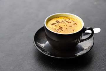 Serving of aromatic turmeric black coffee against dark table