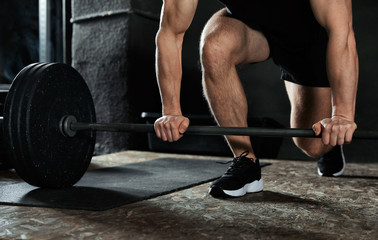 Man lifting barbell in modern gym, closeup