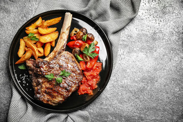 Delicious grilled ribeye served on grey table, flat lay. Space for text