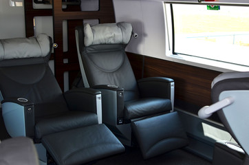 Seats in the cabin of the 1st (business) class carriage of a passenger high speed train. Modern interior of the urban railway transport