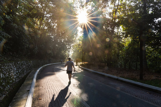 People exercise brisk walk in park with morning sun rays