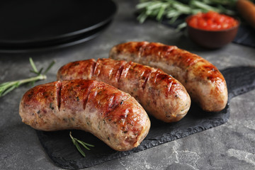 Tasty grilled sausages on grey table, closeup