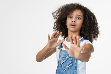 Young beautiful child girl with fear expression stop gesture with hands standing over isolated...