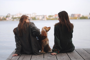 Two girls and english cocker spaniel dog lying on wooden bridge.Portrait of dog outside (outdoors)....