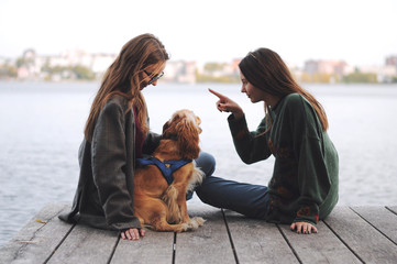 Two girls and english cocker spaniel dog lying on wooden bridge.Portrait of dog outside (outdoors)....