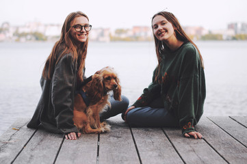 Two girls and english cocker spaniel dog lying on wooden bridge.Portrait of dog outside (outdoors)....