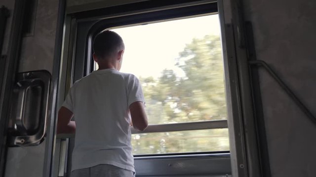The boy looks out the window of the train car. Family travel with children.