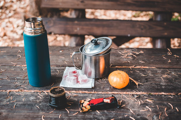 Thermos with coffee, chocolate bar, orange and Turkish delight on wooden table.
