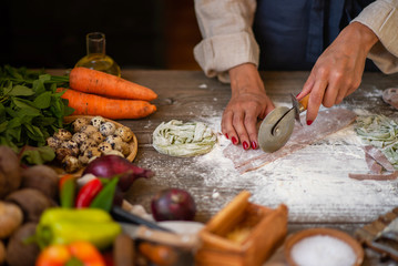 Process of making homemade pasta. Chef make fresh italian traditional pasta. Tasty appetizing classic italian pasta with tomato sauce, cheese parmesan, basil and vegetables on dark table.