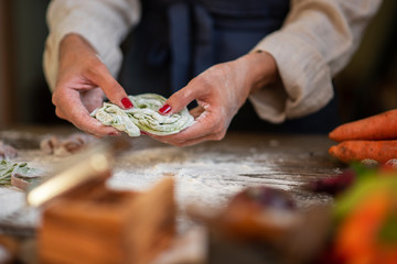 Process of making homemade pasta. Chef make fresh italian traditional pasta. Tasty appetizing classic italian pasta with tomato sauce, cheese parmesan, basil and vegetables on dark table.