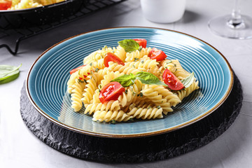 Delicious pasta with tomatoes and basil served on grey table