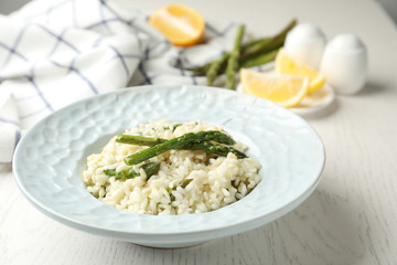 Delicious risotto with asparagus on white wooden table