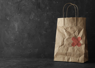 Shopping bag with sticking plasters on grey stone table, space for text