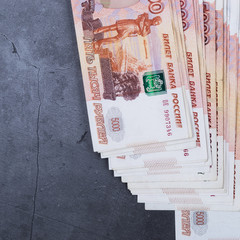 Big stack of Russian money banknotes of five thousand rubles lying on a grey cement background.