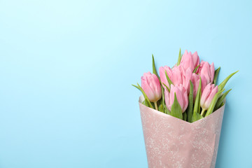 Bouquet of pink tulips on blue background, space for text