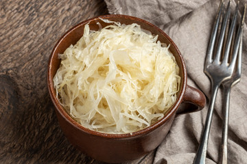 Fermented cabbage in a brown pot, with two forks