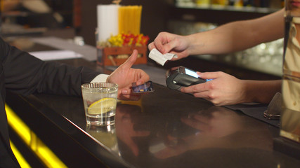 Man pays for cocktail by credit card at the bar