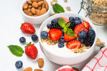 Greek yogurt granola with fresh berries on white table.