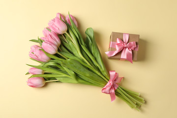 Bouquet of pink tulips and present on beige background, top view