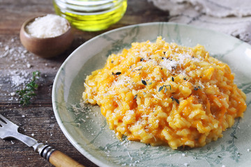 Italian cuisine. Plate of carrot risotto, olive oil and grated parmesan cheese