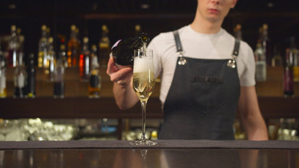 Bartender pours champagne in glass at the bar
