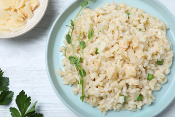 Delicious risotto with cheese on white wooden table, flat lay