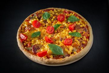 Big italian pizza with tomatoes and basil on a black background.