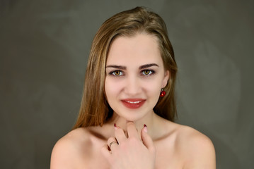 Cosmetics concept, facial skin care. A close-up portrait of a pretty Caucasian model with excellent facial skin and good makeup on a gray background.