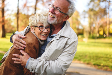 Smiling senior couple walking in the park together enjoying retirement
