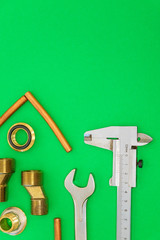 Set of tools and spare parts for plumbing on green background with space for advertising