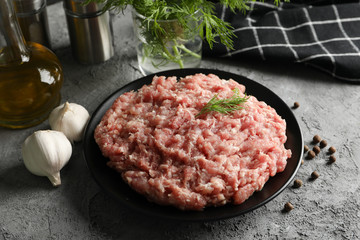 Spices and plate with minced meat on grey background, close up