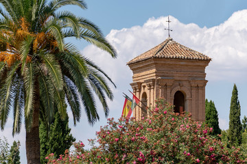 Alhambra Convent of San Francisco of Granada tower with a colorful garden and a palm tree, spain