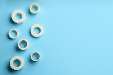 Sticking plaster rolls on light blue background, flat lay. Space for text