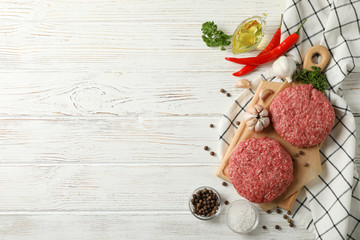 Spices and cutting board with minced meat on wooden background, space for text