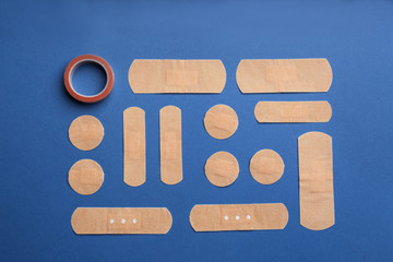 Different types of sticking plasters on blue background, flat lay