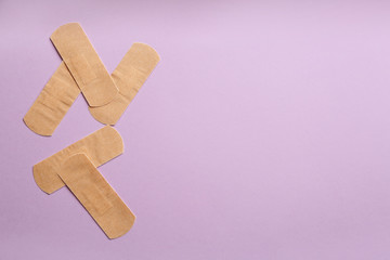 Sticking plasters on lilac background, flat lay. Space for text