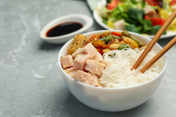 Tasty cooked rice noodles with chicken and vegetables on grey marble table