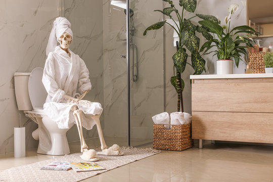Skeleton in bathrobe sitting on toilet bowl