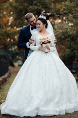 Bride and groom in wedding day. Bride and groom on a wedding walk in the park. Tender feelings for newlyweds. Couple in love. Bridal bouquet. Luxury dress 
