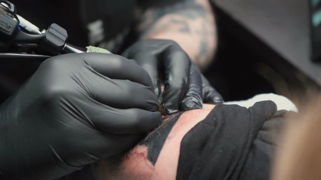 Footage of professional getting black tattoo of snake in studio