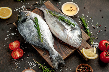 Fresh dorado fish with spices and ingredients tomato, razmorin, sunflower oil, lemon for cooking on a stone background