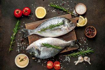 Fresh dorado fish with spices and ingredients tomato, razmorin, sunflower oil, lemon for cooking on a stone background