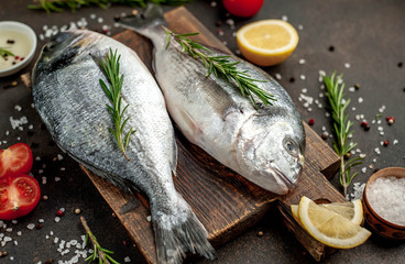 Fresh dorado fish with spices and ingredients tomato, razmorin, sunflower oil, lemon for cooking on a stone background