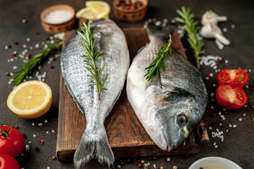 Fresh dorado fish with spices and ingredients tomato, razmorin, sunflower oil, lemon for cooking on a stone background