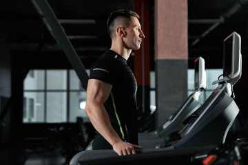 Fototapeta na wymiar Man working out on treadmill in modern gym