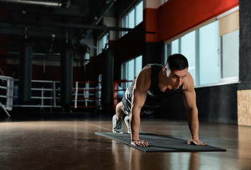 Fototapeta na wymiar Man doing plank exercise in modern gym