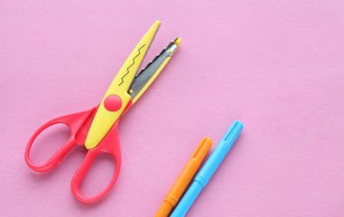 scissors, ruler and crayons on a pink background. Creative, fashionable, minimalistic, school or office workspace with yellow supplies for handycraft on cyan background. Flat lay.