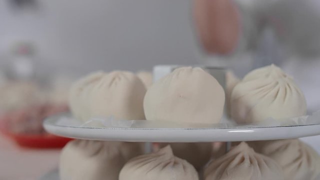 Close-up: a woman's hand puts a delicious buuz (Manty) on the grill for steaming. Traditional Mongolian cuisine, cooking meat and dough with your own hands. Hearty food, Asian cuisine, 4K, Red Epic