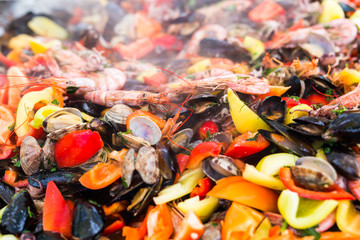 Street food concept - Gourmet seafood paella with pink marine prawns and mussels on yellow saffron rice with peas and bell peppers