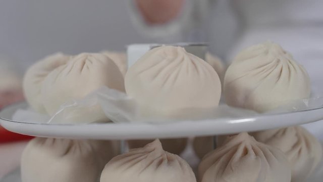 Close-up: a woman's hand puts a delicious buuz (Manty) on the grill for steaming. Traditional Mongolian cuisine, cooking meat and dough with your own hands. Hearty food, Asian cuisine, 4K, Red Epic